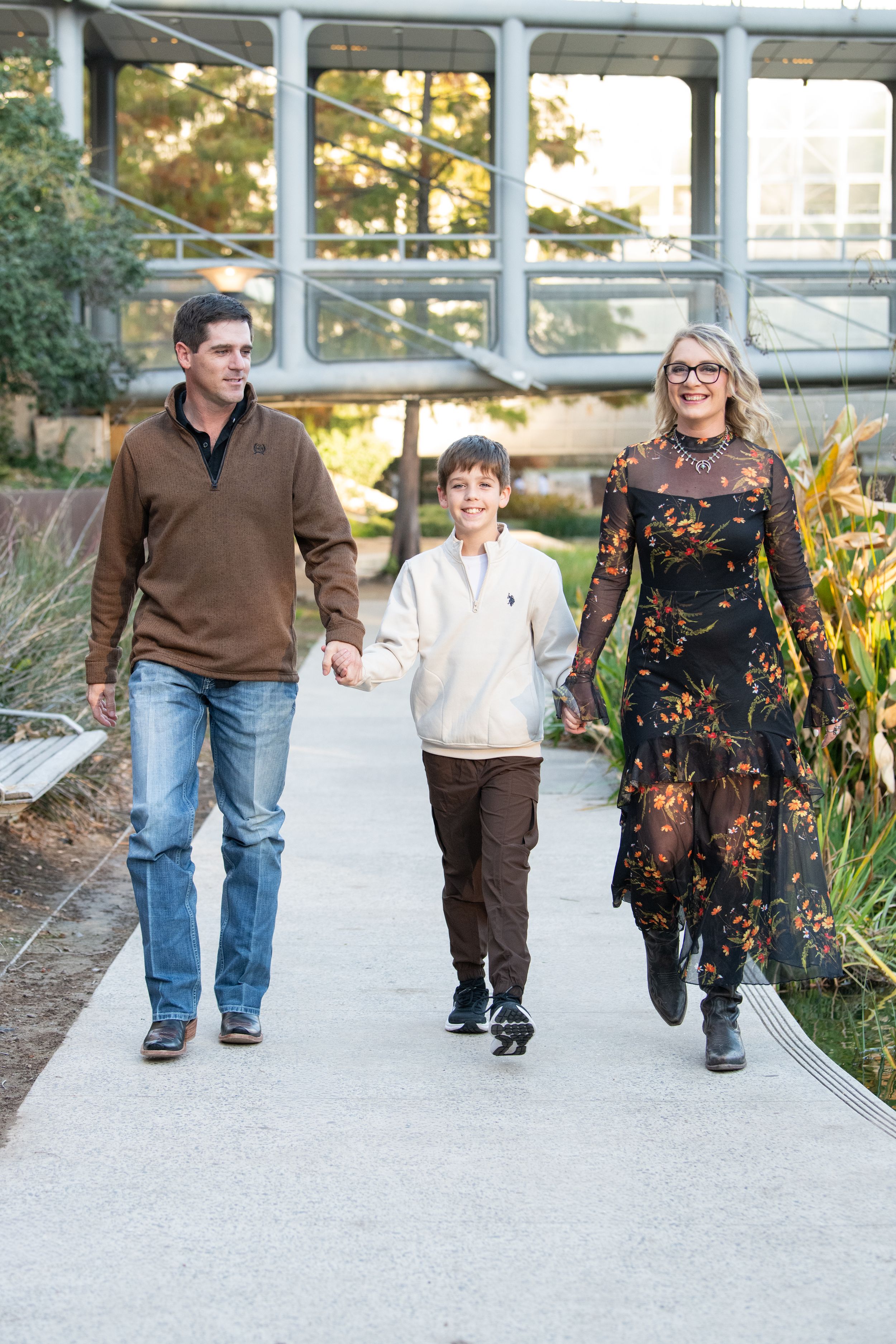 Group walking together on a paved pathway surrounded by landscaping and architectural columns.
