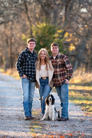 A family poses with their Border Collie dog on an autumn path.