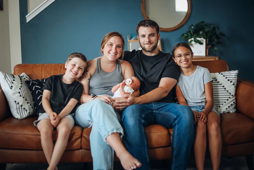 Family sitting together on a blue couch for casual indoor portraits. Family photography