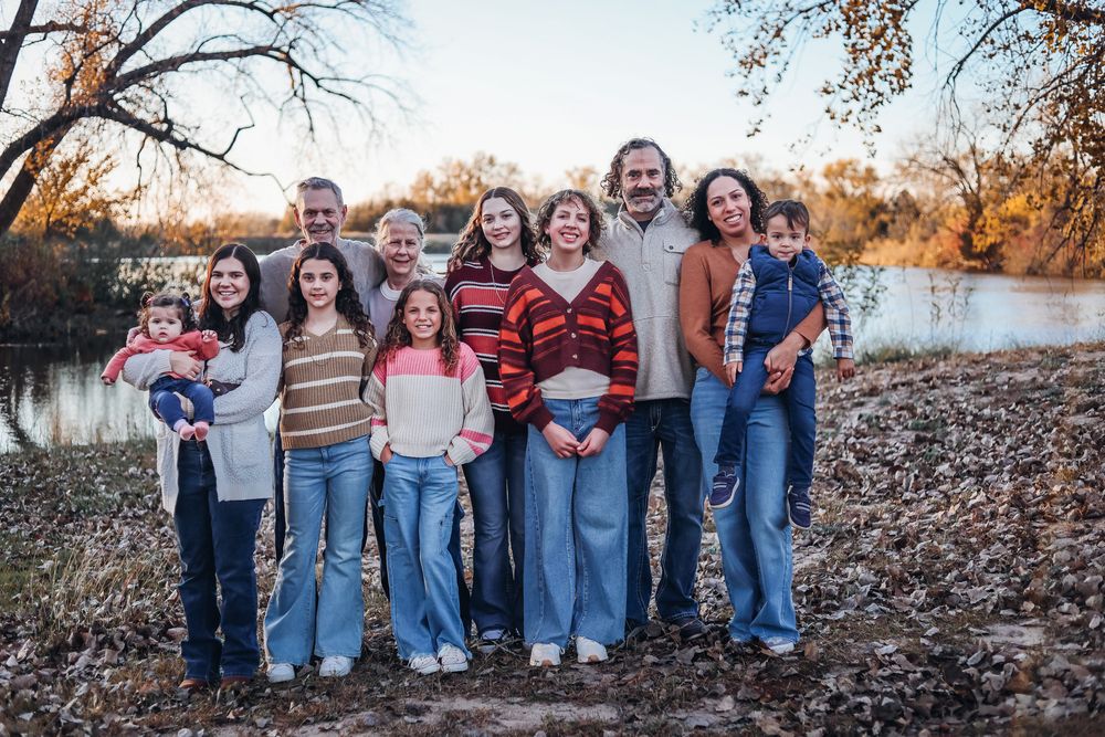 Group photo of people in casual wear sitting together on fallen autumn leaves. Extended family photography