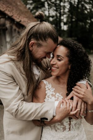 Bruid en bruidegom leggen voorhoofden tegen elkaar aan voor een liefdevolle portretfoto