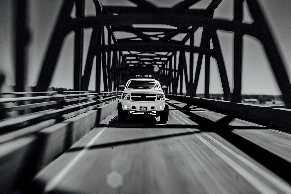 Dramatic black and white photo of vehicle driving through geometric bridge tunnel.