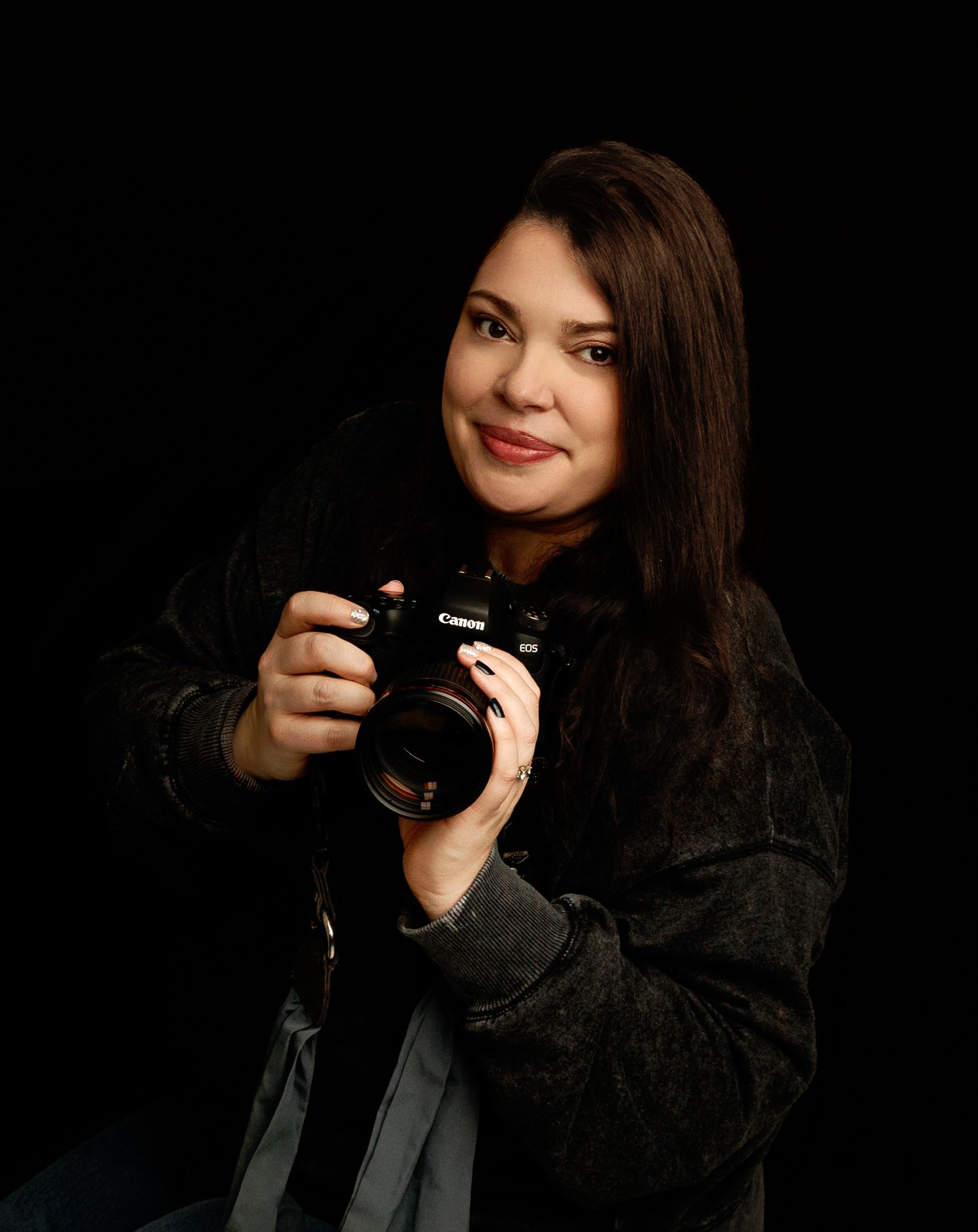 Stephanie Ann Benson, maternity and newborn photographer in Tilton NH, holding a camera in her photography studio