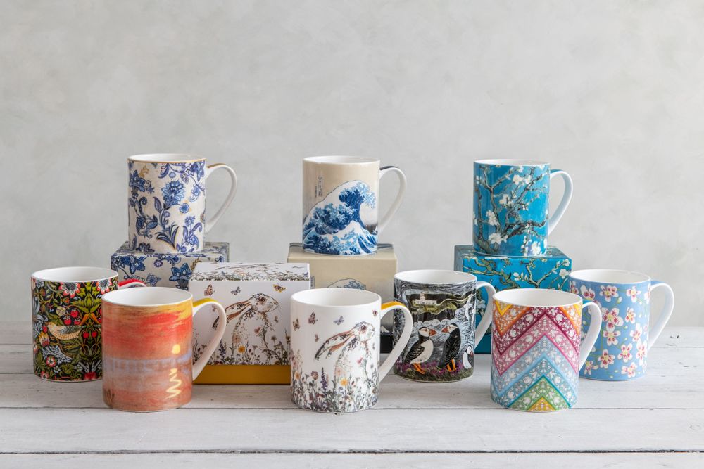 Collection of patterned ceramic mugs arranged in rows on a white surface.