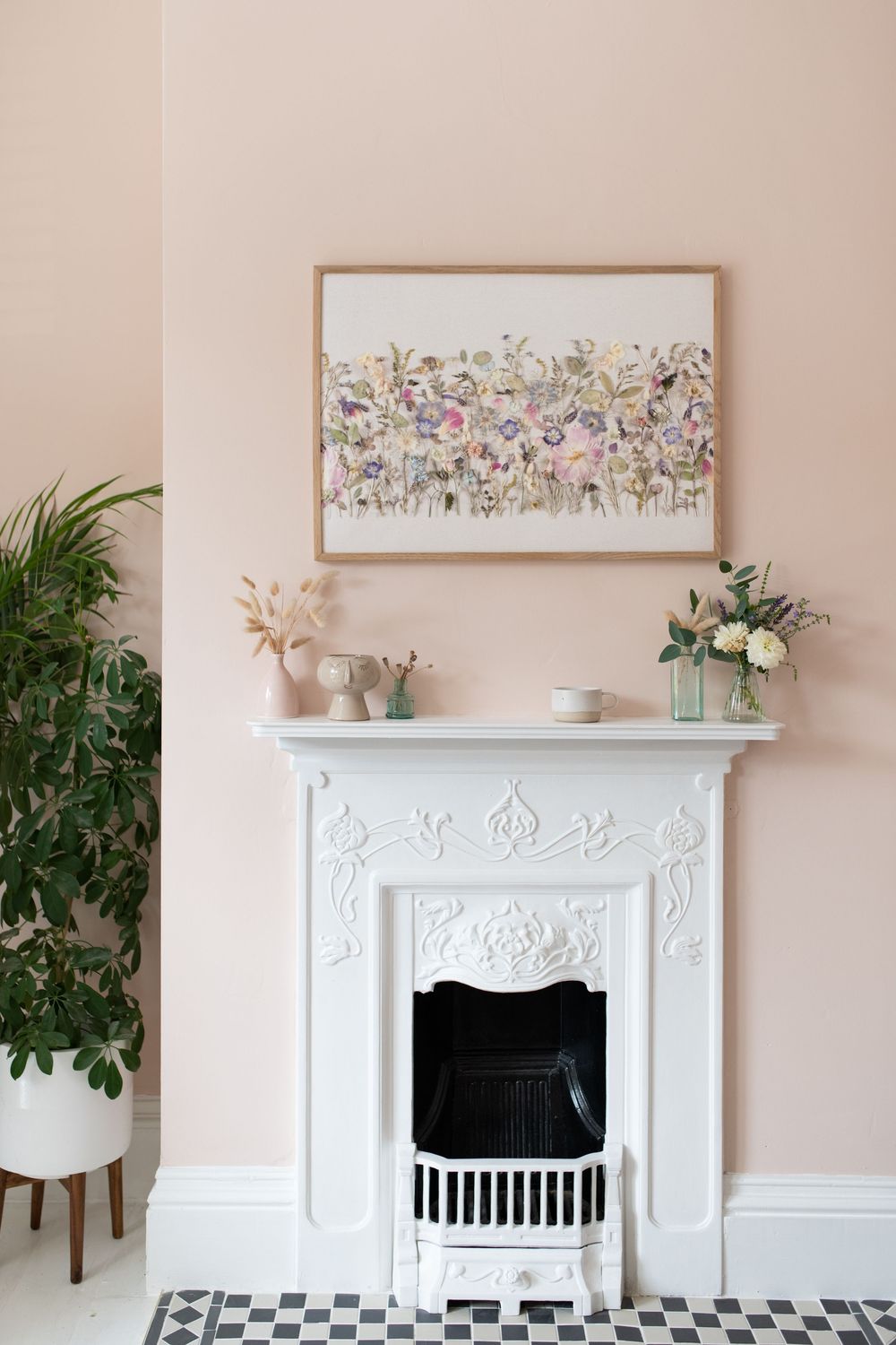 Styled living room with framed floral artwork above a white fireplace and indoor plants.