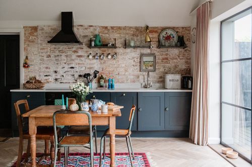 Modern dining room with exposed brick walls, wooden table, and black pendant light showcases rustic-industrial design elements.