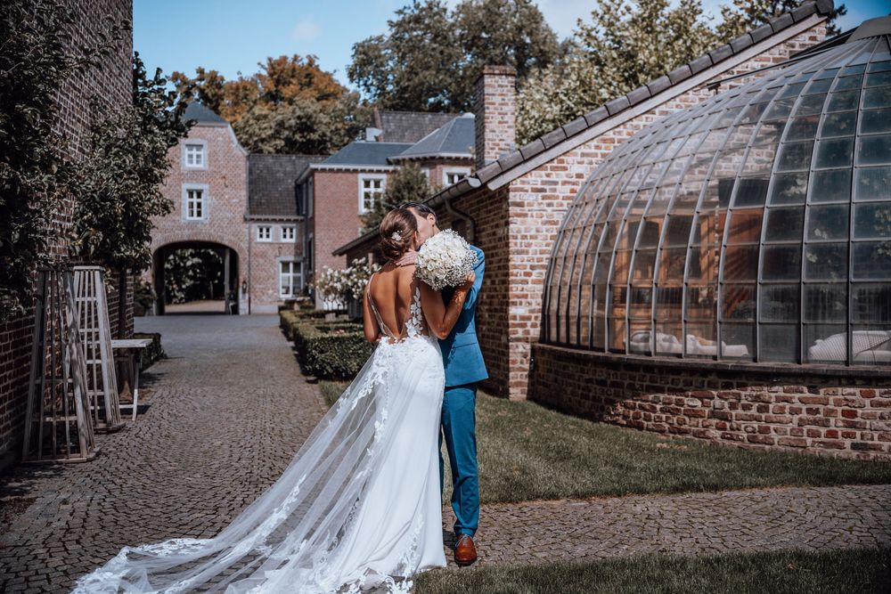 Twee mensen beleven een romantisch moment bij een vintage glazen koepel op een elegant landgoed met bakstenen gebouwen.