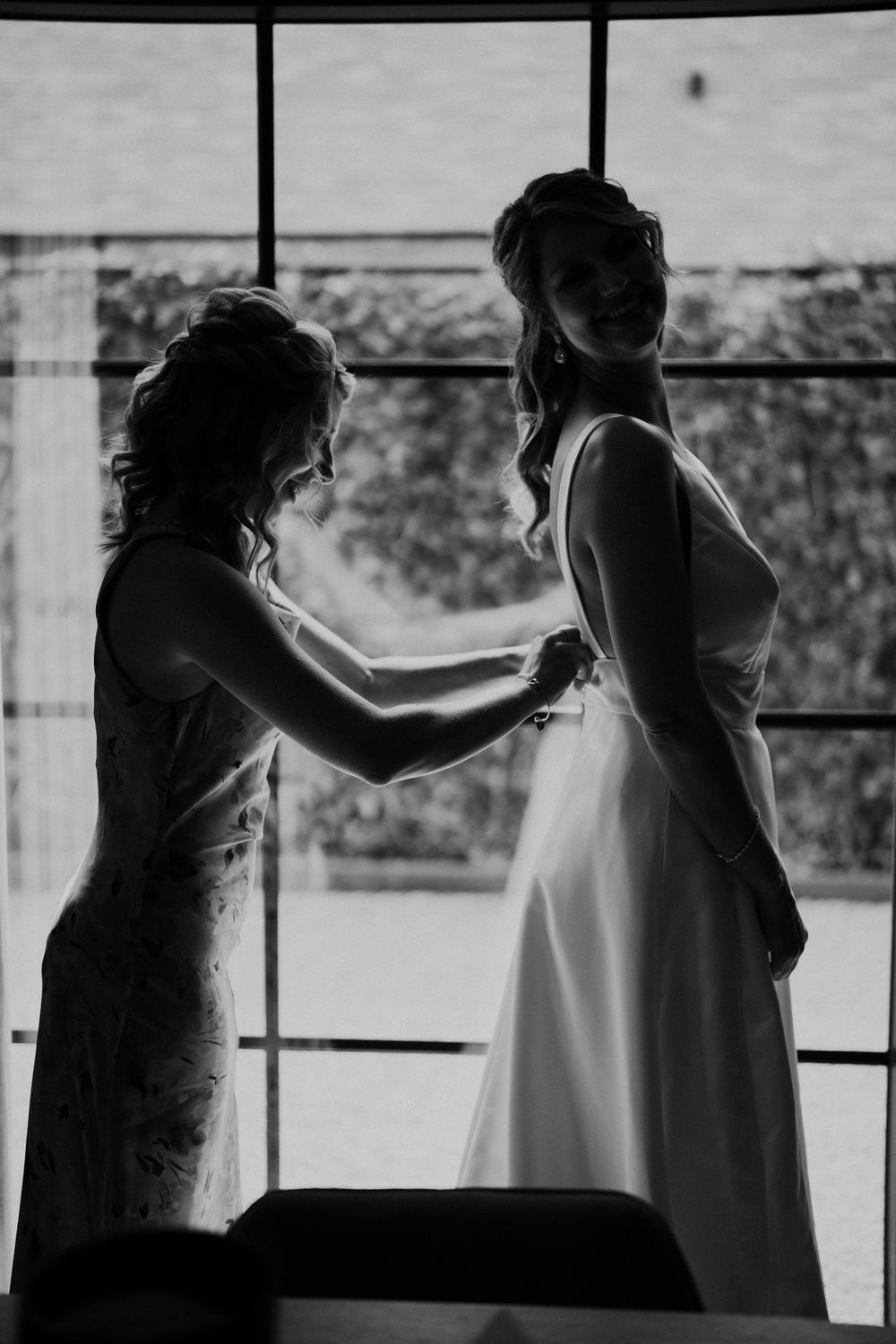Silhouet van bruidsjurk voorbereidingsmoment door groot raam.