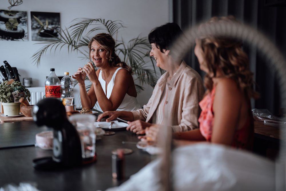 Voorbereidingen op de ochtend van de bruiloft met gasten die genieten van verfrissingen aan de eettafel.