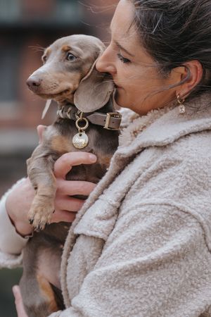 Mensch-Hund-Fotografie: Frau hält ihren kleinen Hund nah bei sich, fotografiert im Grünen nahe Hohenkammer.
