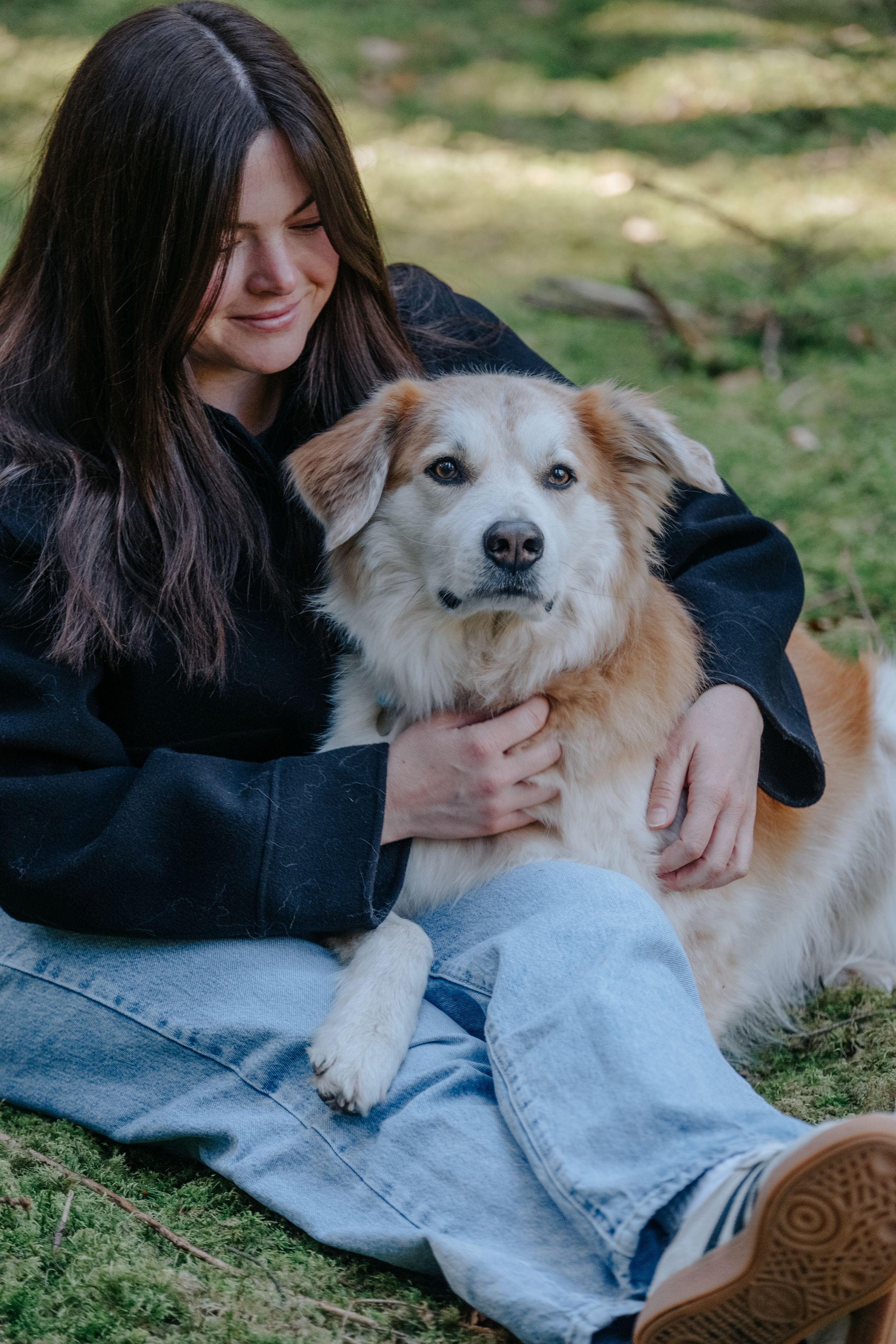 Mensch-Hund-Fotografie: Frau sitzt mit ihrem Hund auf einer Wiese, natürliche Aufnahme nahe Freising.