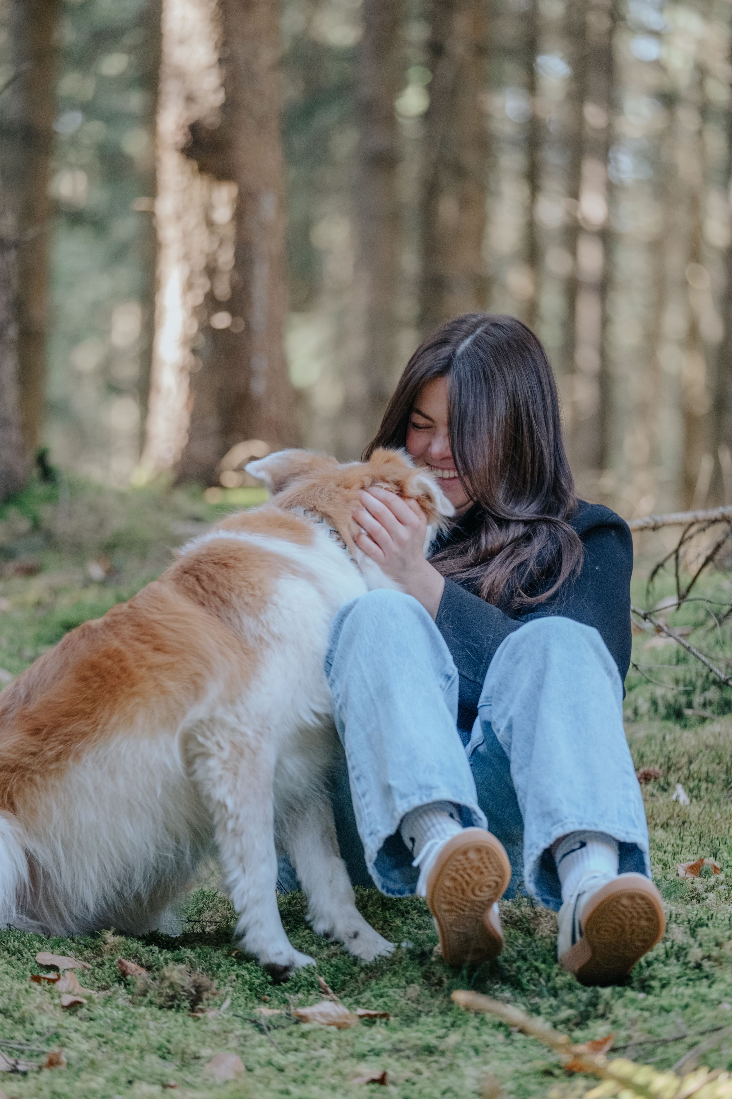 Mensch-Hund-Fotografie: Frau sitzt mit ihrem Hund im Wald und hält ihn nah bei sich, fotografiert bei Pfaffenhofen a. d. Ilm.