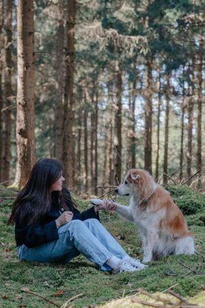 Mensch-Hund-Fotografie: Frau sitzt mit ihrem Hund auf dem Waldboden, ruhiger Moment im Wald bei Pfaffenhofen a. d. Ilm.