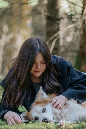 Mensch-Hund-Fotografie: Frau liegt mit ihrem Hund im Gras und blickt ihn ruhig an, aufgenommen im Raum Hohenkammer.