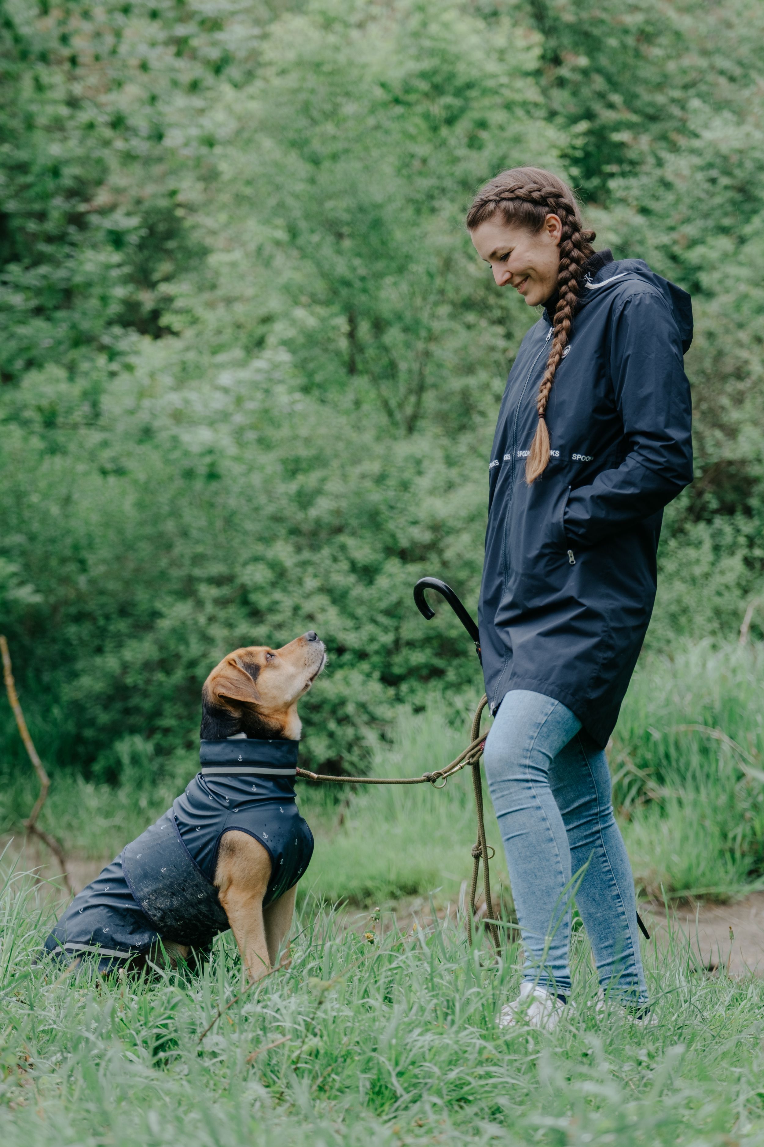 Mensch-Hund-Fotografie: Frau steht mit ihrem Hund auf einem Waldweg nahe Freising, ruhiger Moment im natürlichen Umfeld.