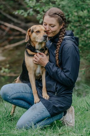 Mensch-Hund-Fotografie: Frau kniet im Gras und hält ihren Hund im Arm, natürliche Aufnahme nahe Dachau.