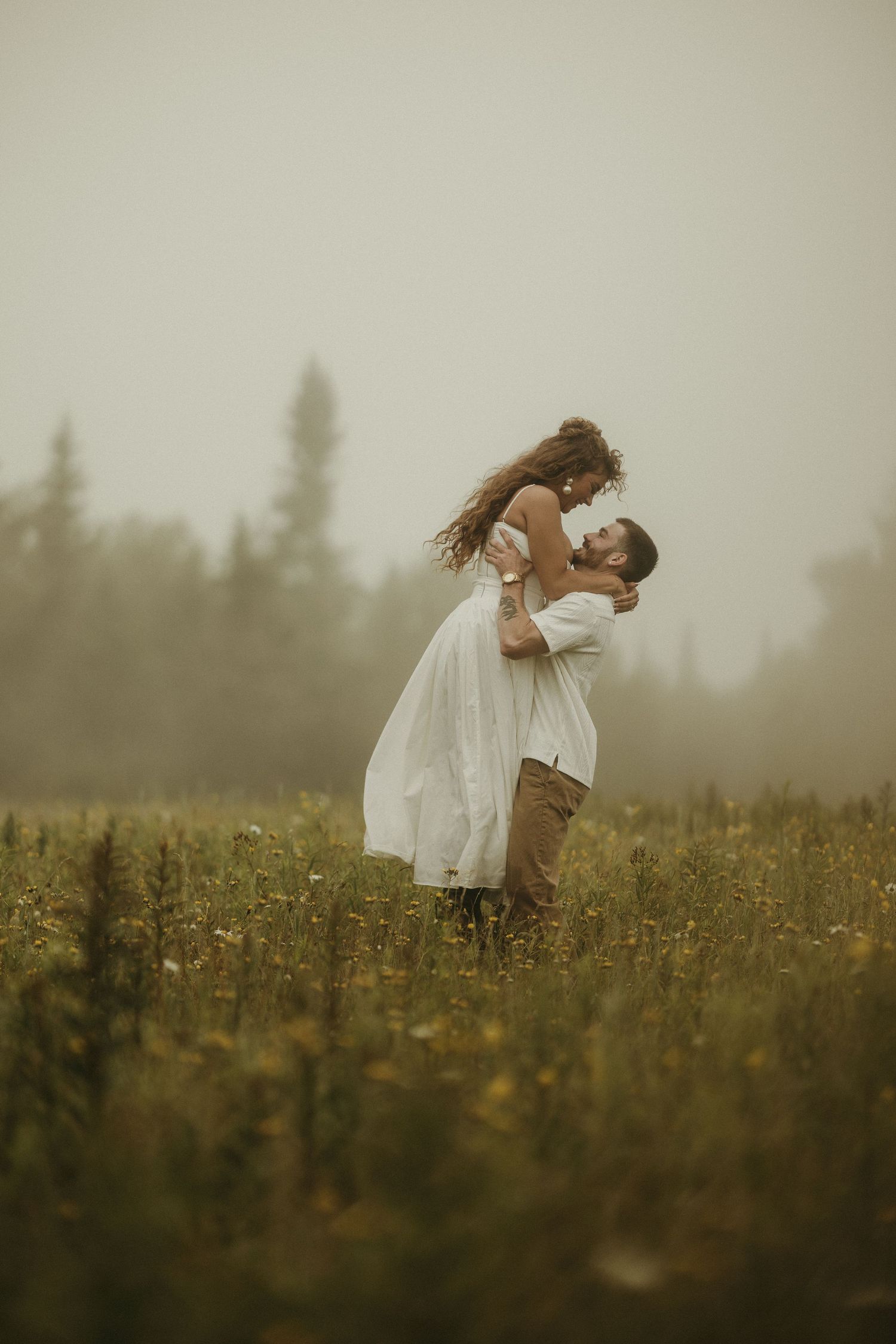 A figure in a white dress dances gracefully through a misty wildflower meadow at dusk.