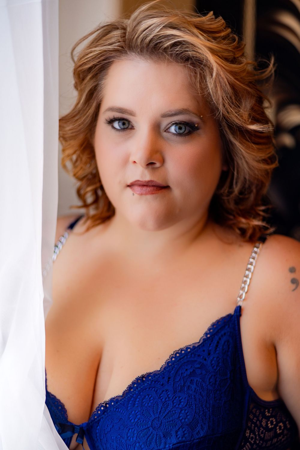 Glamour portrait in a royal blue lace dress against soft lighting.