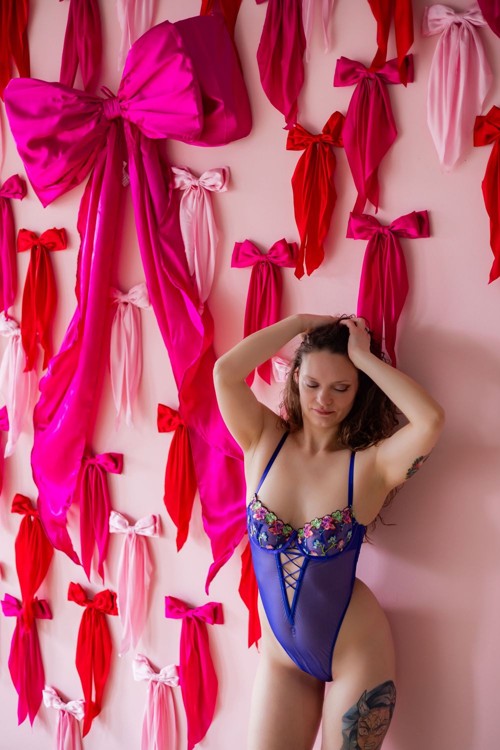 Pink and red ribbon bows create a decorative backdrop against a light colored wall.
