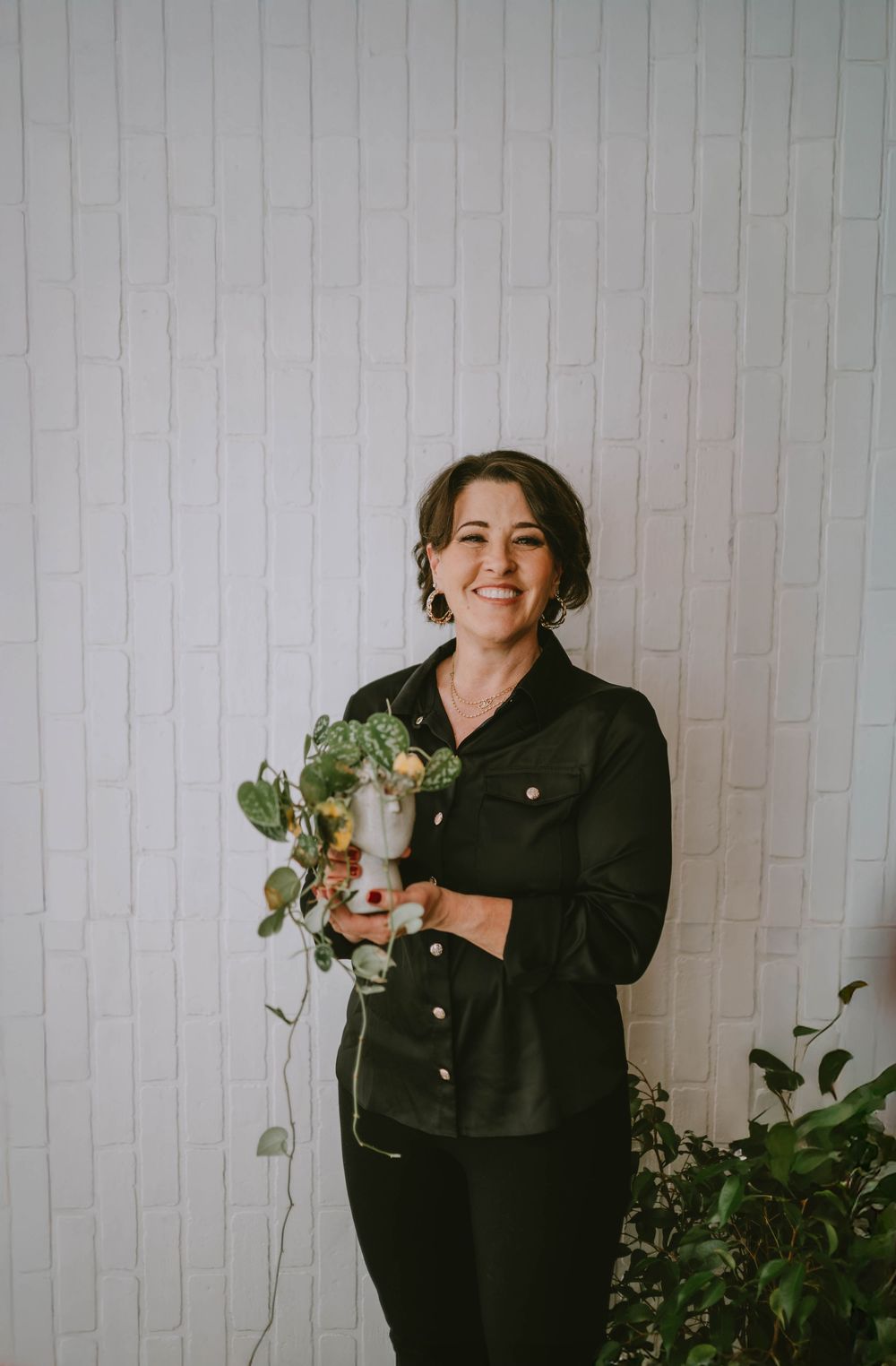 A series of candid shots showing someone in a black jacket posing against a white wall with plants.