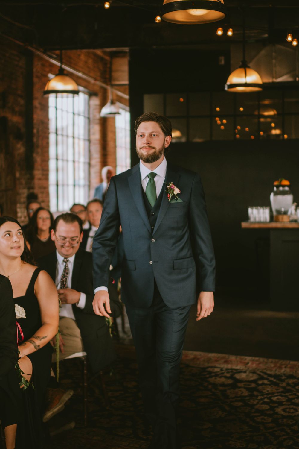 Wedding reception scene in a rustic brick venue with guests in formal attire.