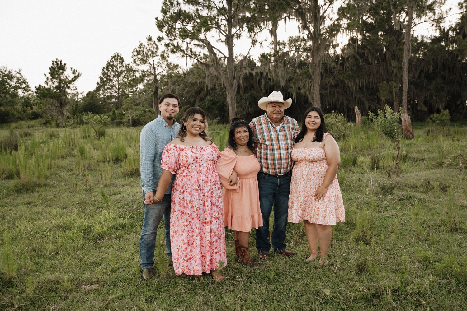 Group of people standing together outdoors at sunset in casual clothing.