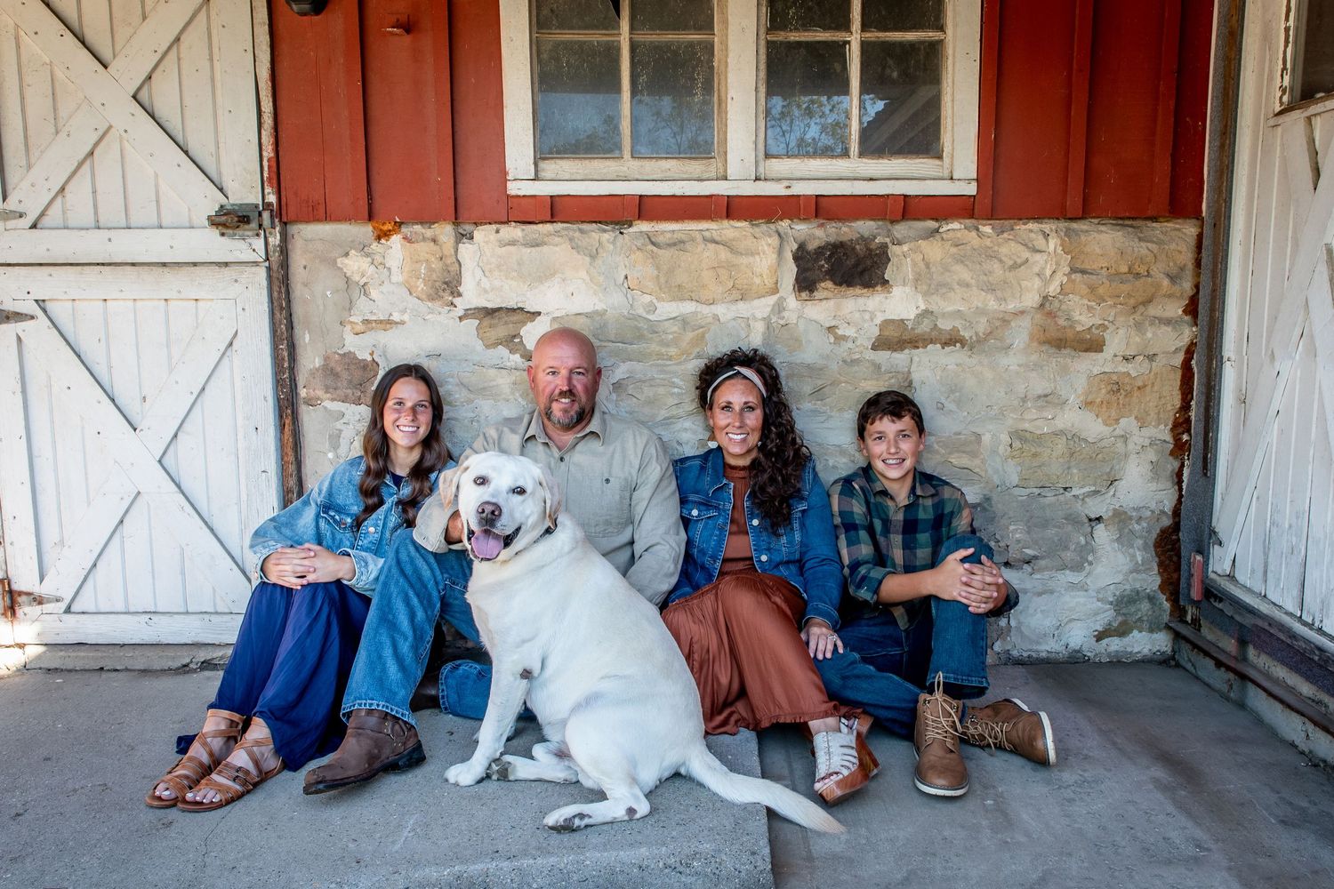 Casual family portrait with a white dog sitting on a rustic stone porch.