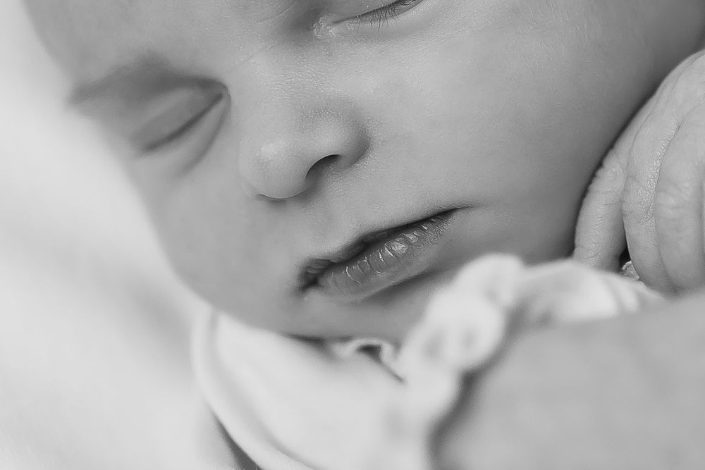 A newborn baby sleeps gently in black and white in home portrait