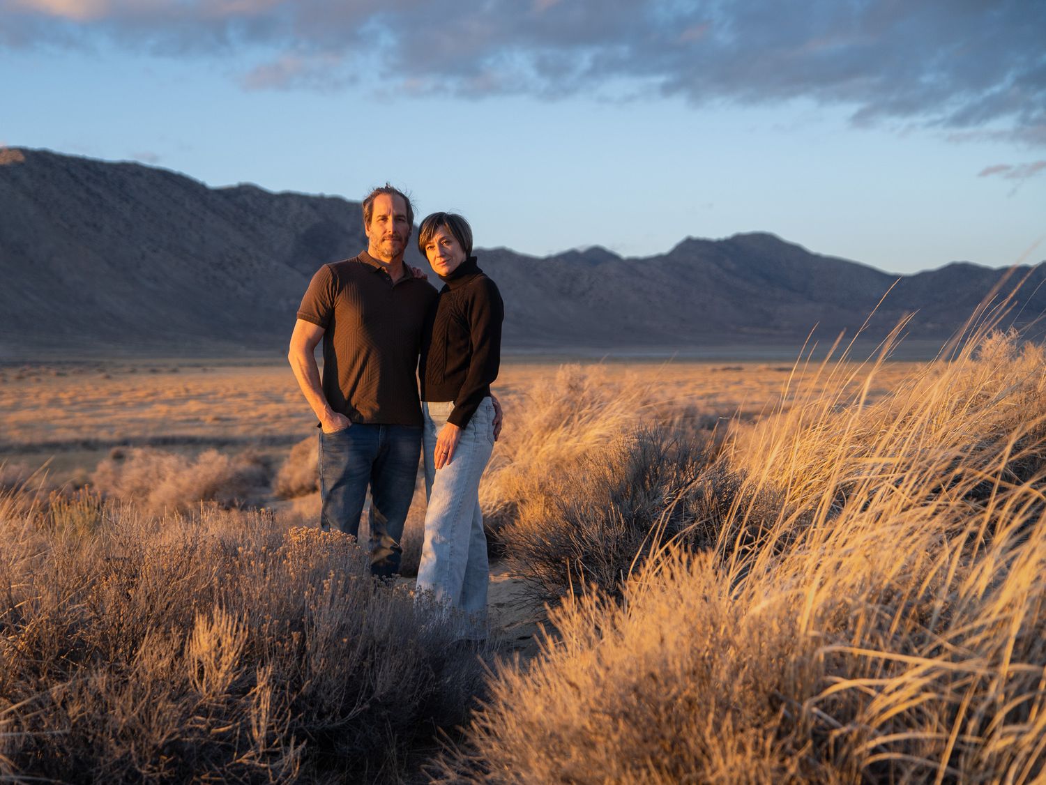 An outdoor portrait at sunset with golden grasses and mountains in the background.