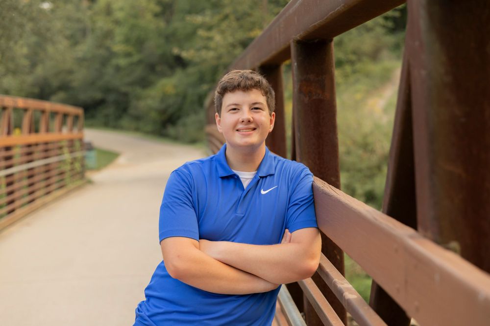 teenage boy leaning against a bridge at riverbends park