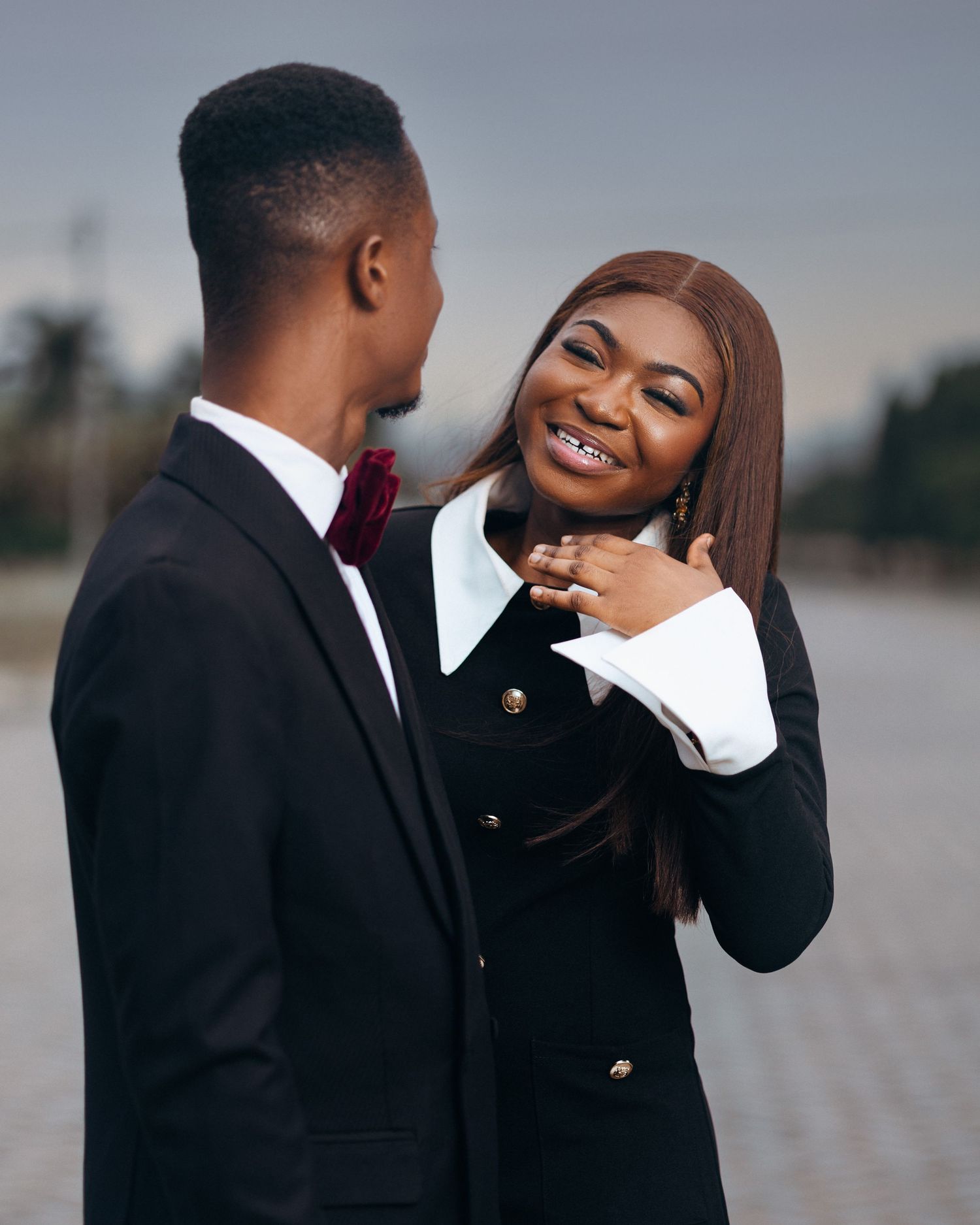 A romantic couple shares tender moments in formal attire during an outdoor photo session at dusk.
