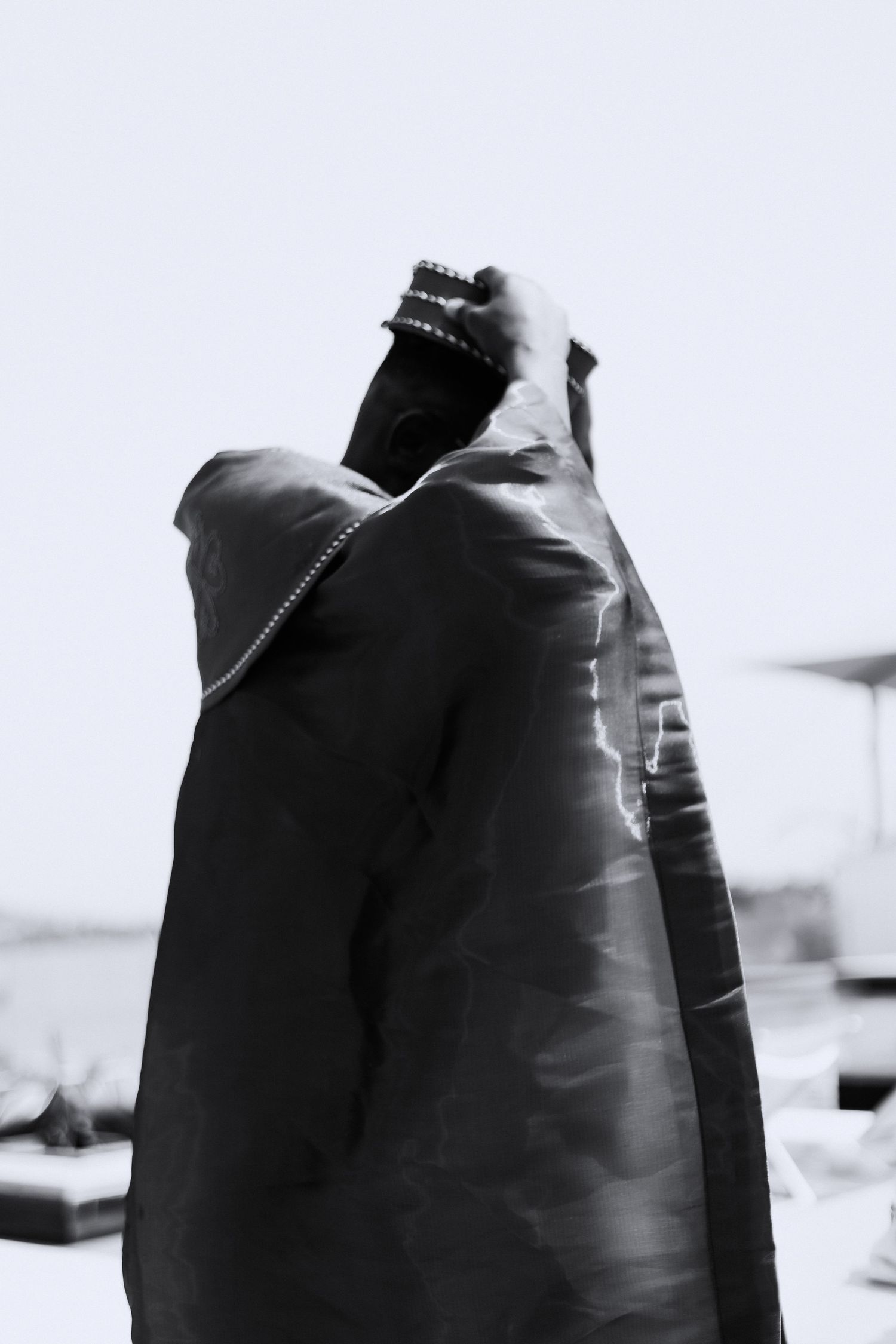 A black and white artistic photograph shows a silhouetted figure in motion wearing dark clothing.