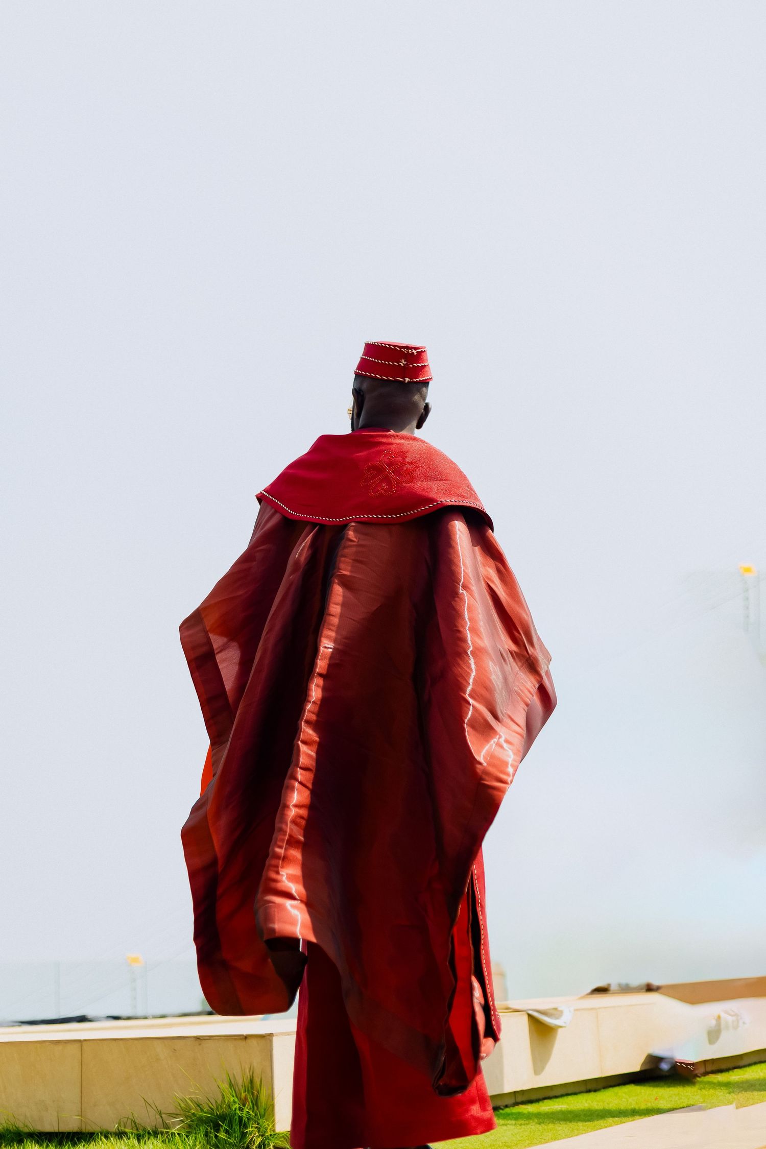 Red shirt drying on a clothesline against a light background with a grassy lawn visible below.
