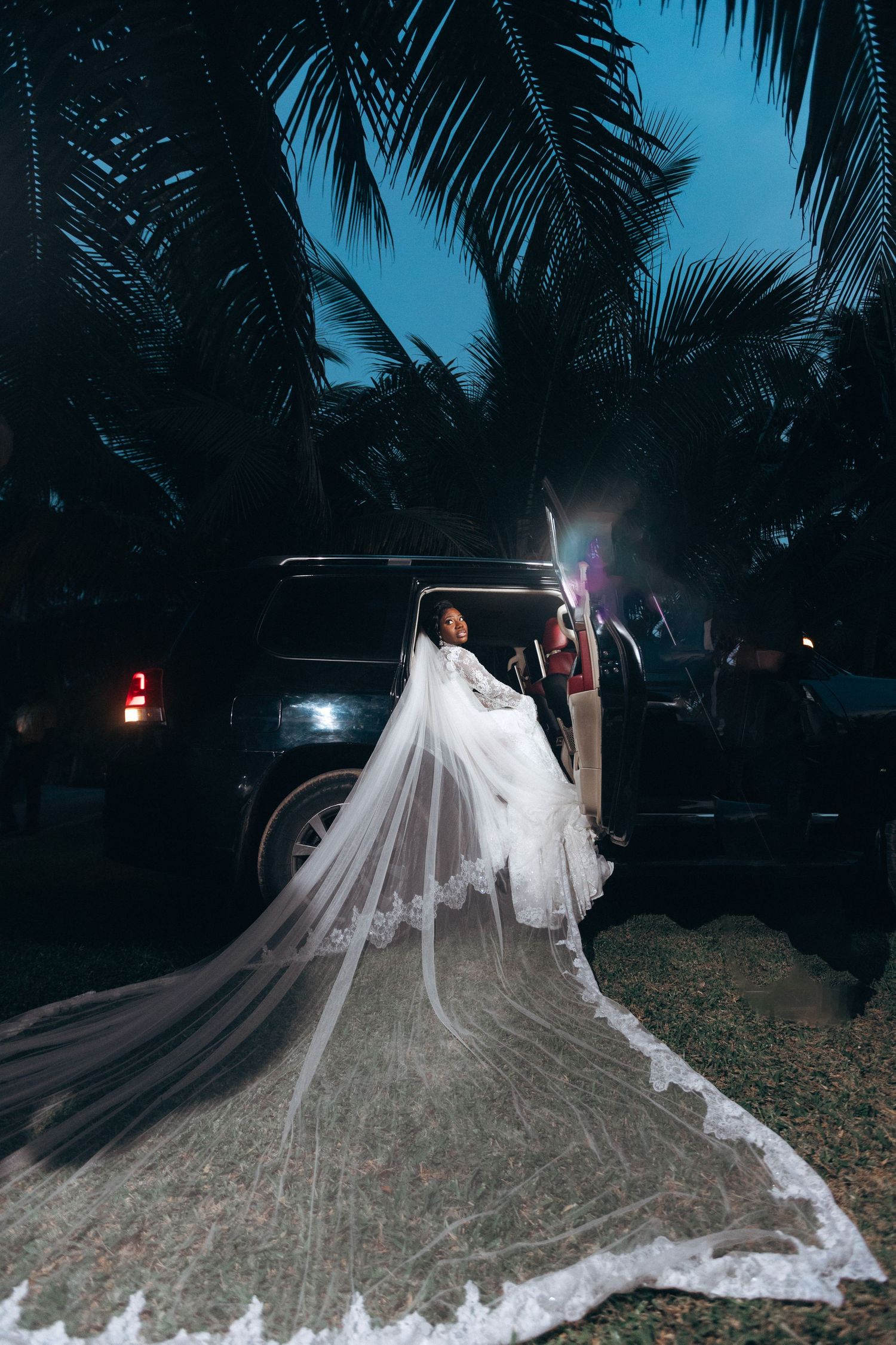 A dramatic wedding photo at night shows a flowing white cathedral-length veil against palm trees and a parked car.