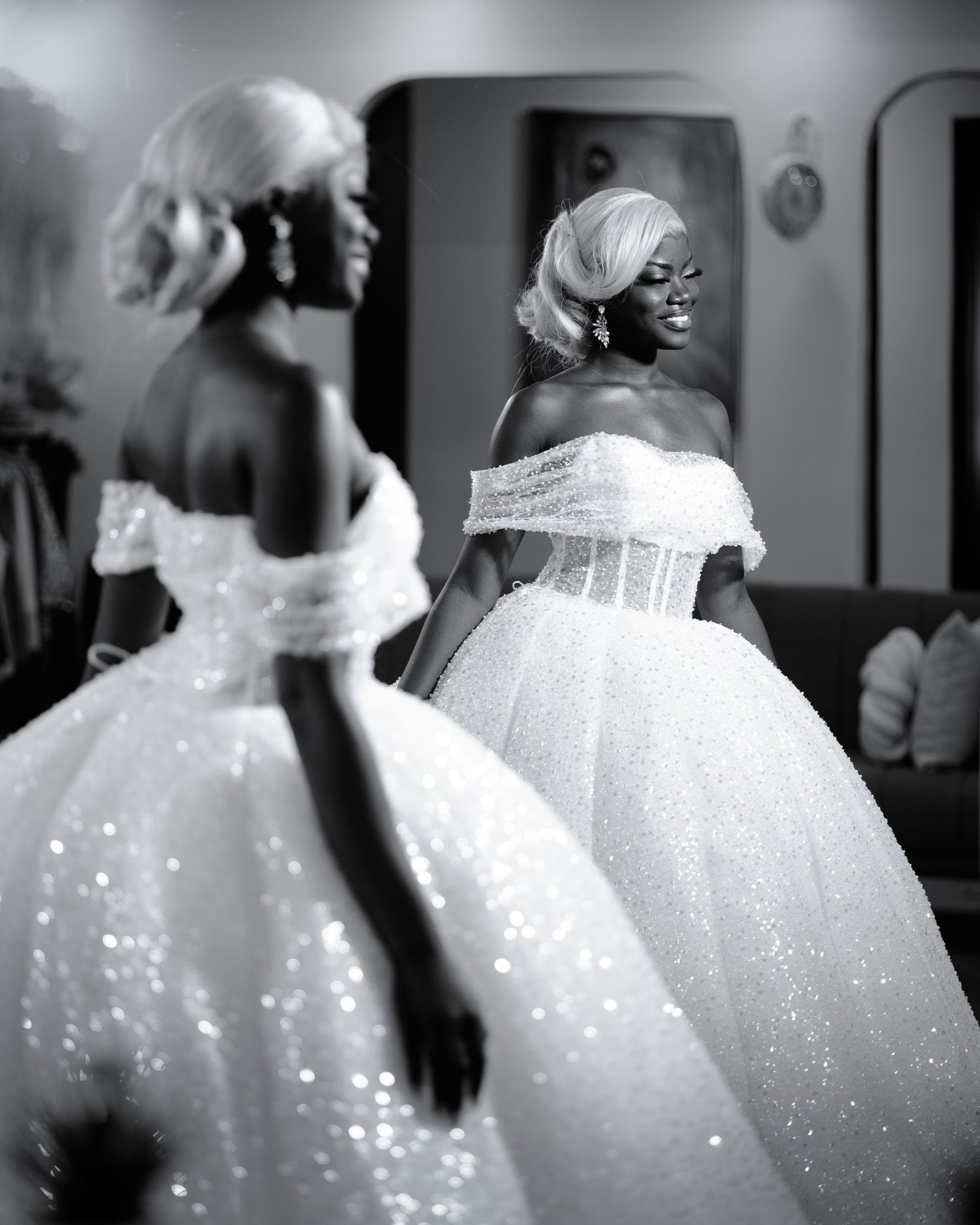 Bride in a sparkling white ballgown poses with her reflection in a mirror.