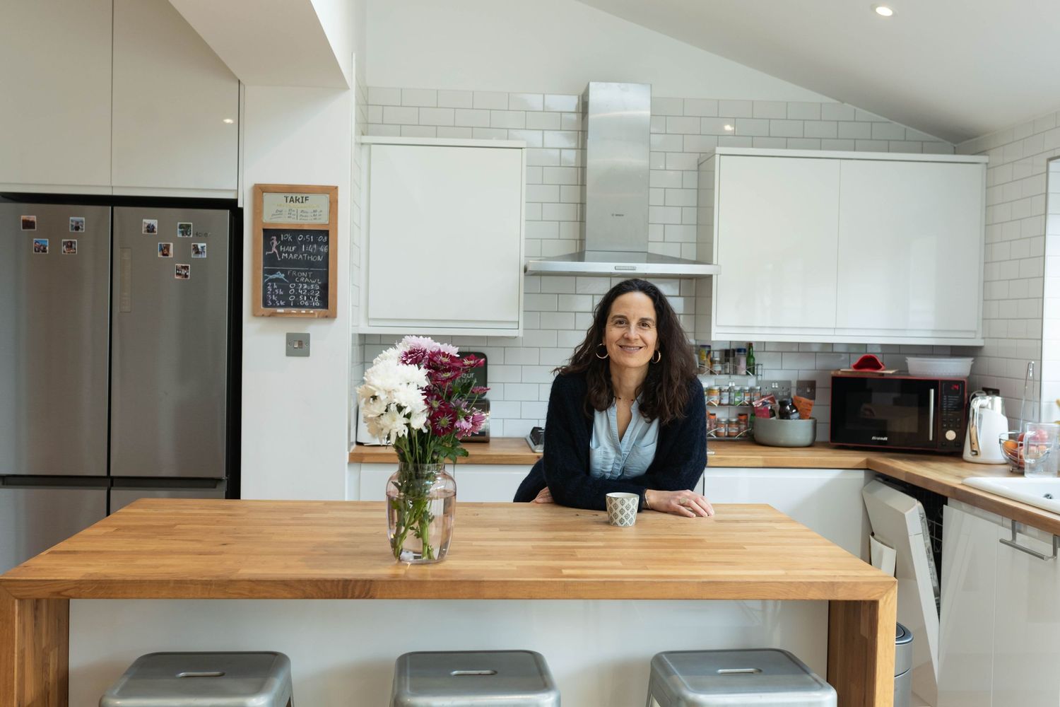 Photo of a female confidence coach in her kitchen during a branding photography shoot in Brighton. She is smiling and standing confidently,