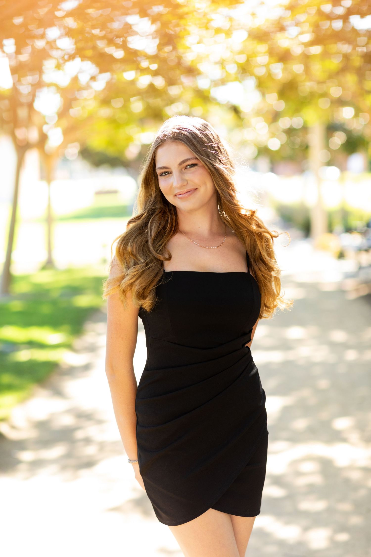 A high school senior  in a vibrant red dress with puff sleeves poses against a white brick wall background.