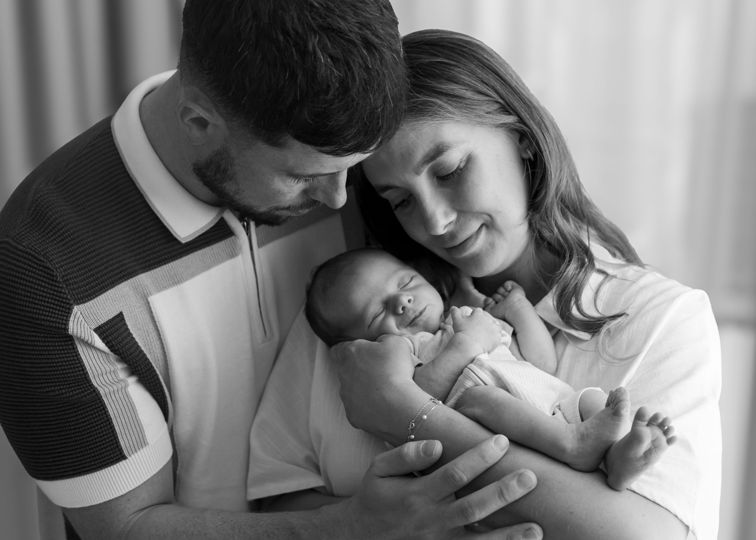 Carlene Thurston Photography - `at-home newborn shoot. baby being held by mum and dad in a standing pose for a natural newborn photoshoot.
