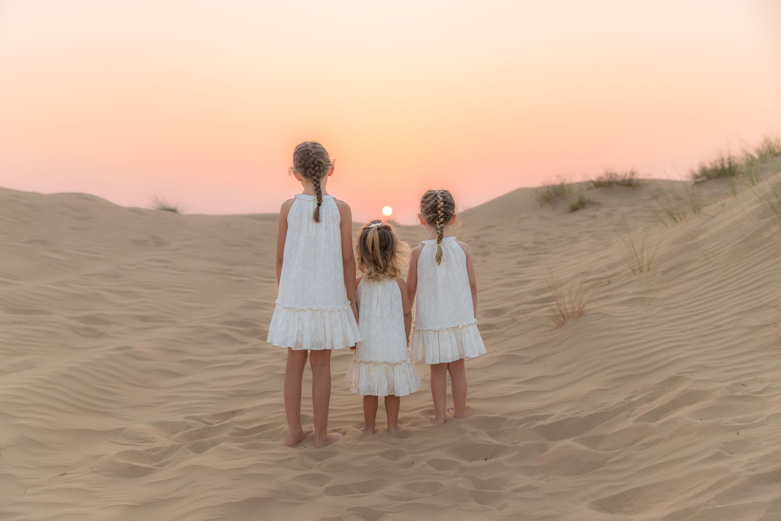 Dubai Family Photographer Carlene Thurston captures stunning sunset photo in the Dubai desert of 3 sisters on the dunes