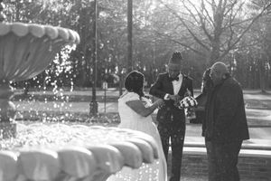 Black and white photo of people near a decorative fountain in a park setting on a sunny day.