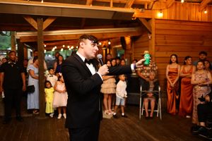 People dance in a rustic wooden barn venue during a wedding reception with warm lighting and onlooking guests.