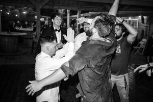 A lively dance party scene captured in black and white with people enthusiastically dancing and celebrating at a gathering.