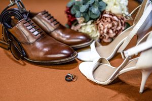 Brown leather formal shoes paired with cream high heels on a brown suede background.