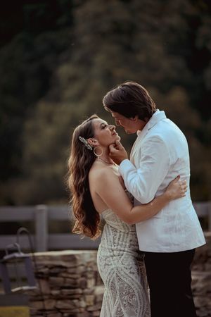 A romantic couple shares an intimate dance together outdoors against a natural backdrop at sunset.