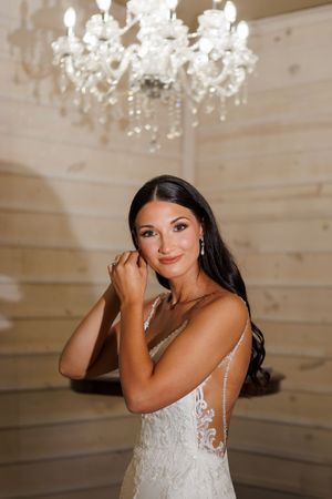Elegant bridal portraits under crystal chandelier in white wedding dress.