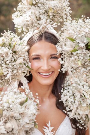 Delicate white baby's breath flowers frame a bridal portrait against a soft natural background.