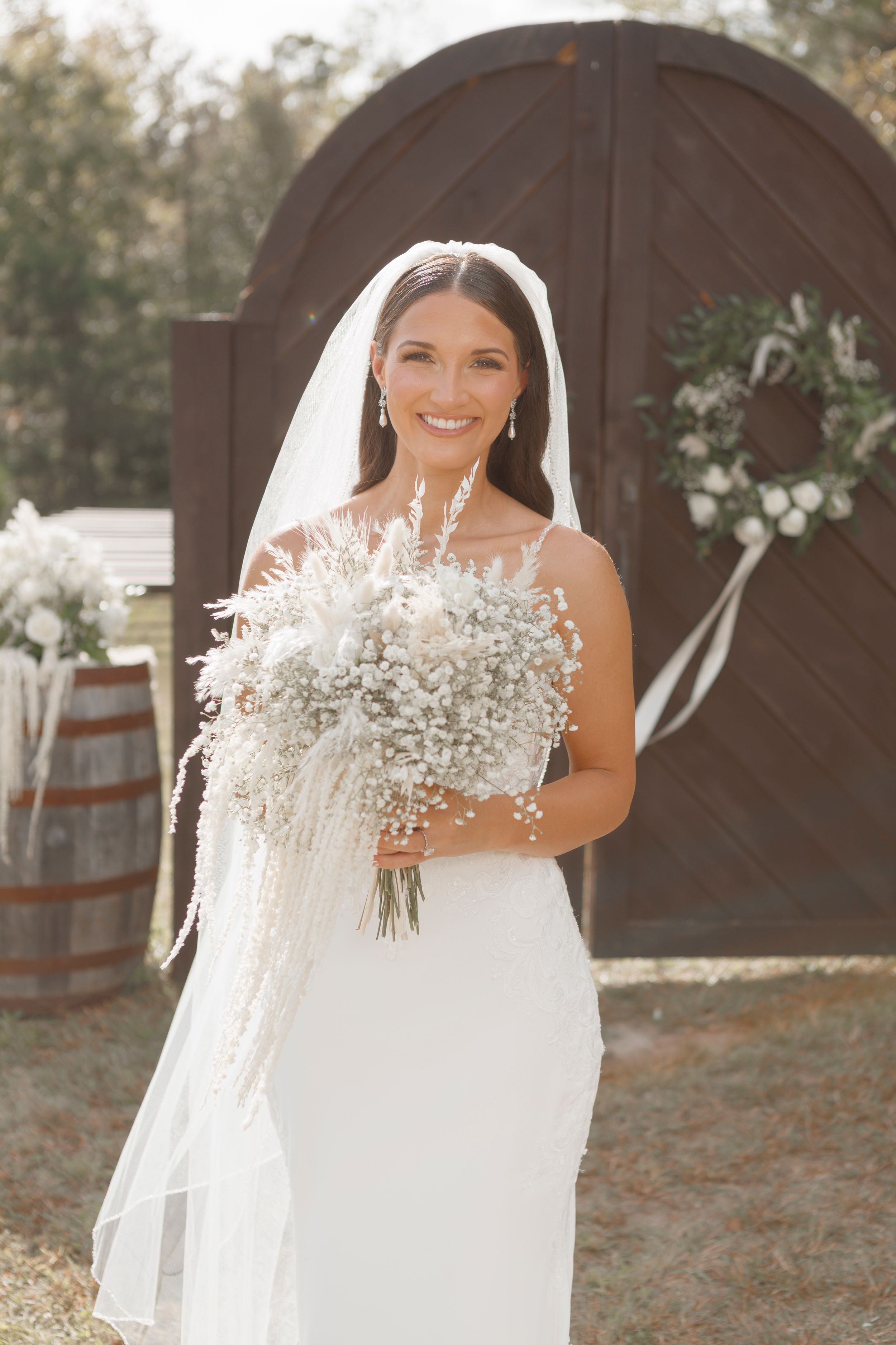 A beautiful white wedding bouquet with delicate baby's breath flowers held against a flowing bridal gown.
