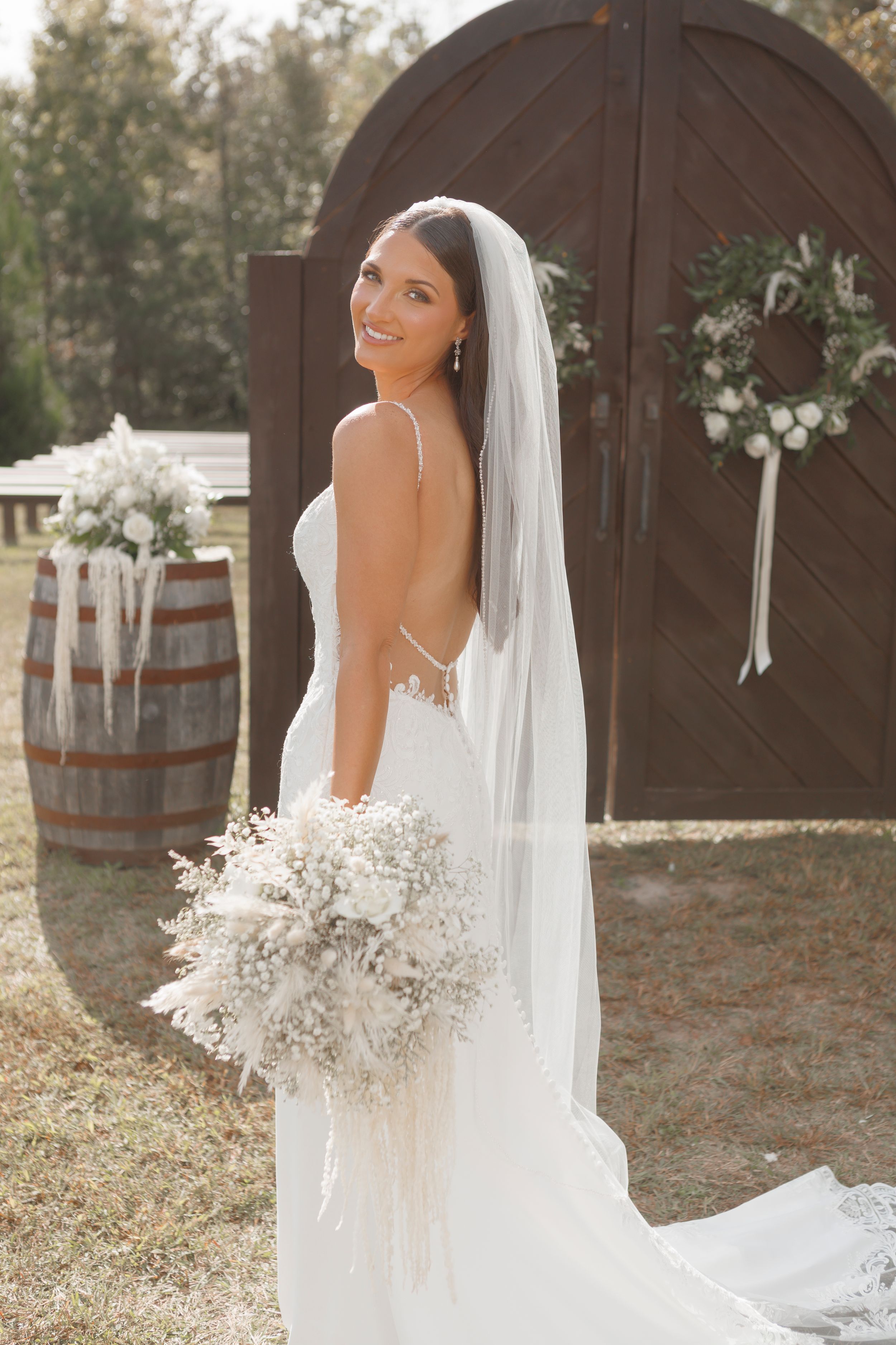 Elegant bridal portraits showcasing a white wedding gown and bouquet in front of a rustic wooden backdrop.