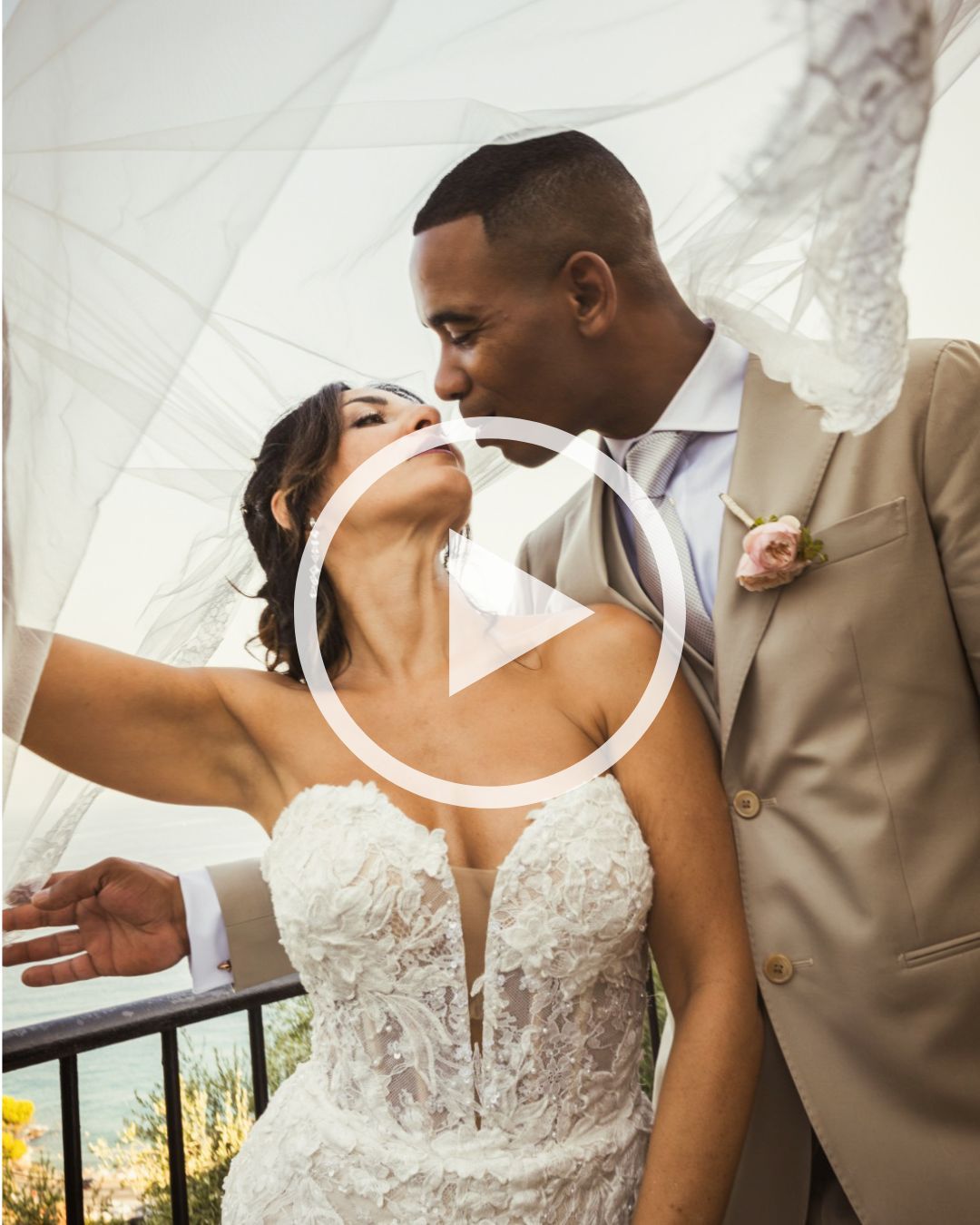 A bride and groom share a romantic kiss under a flowing white veil on their wedding day.