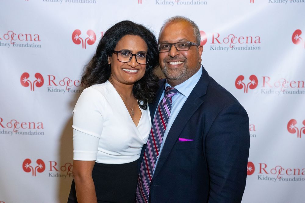 Two people pose together at a Roena Kidney Foundation event in front of a branded step-and-repeat backdrop.